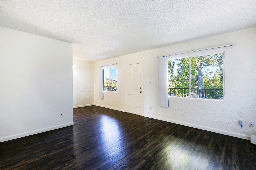 A room with a white door and a window with a view of trees outside.