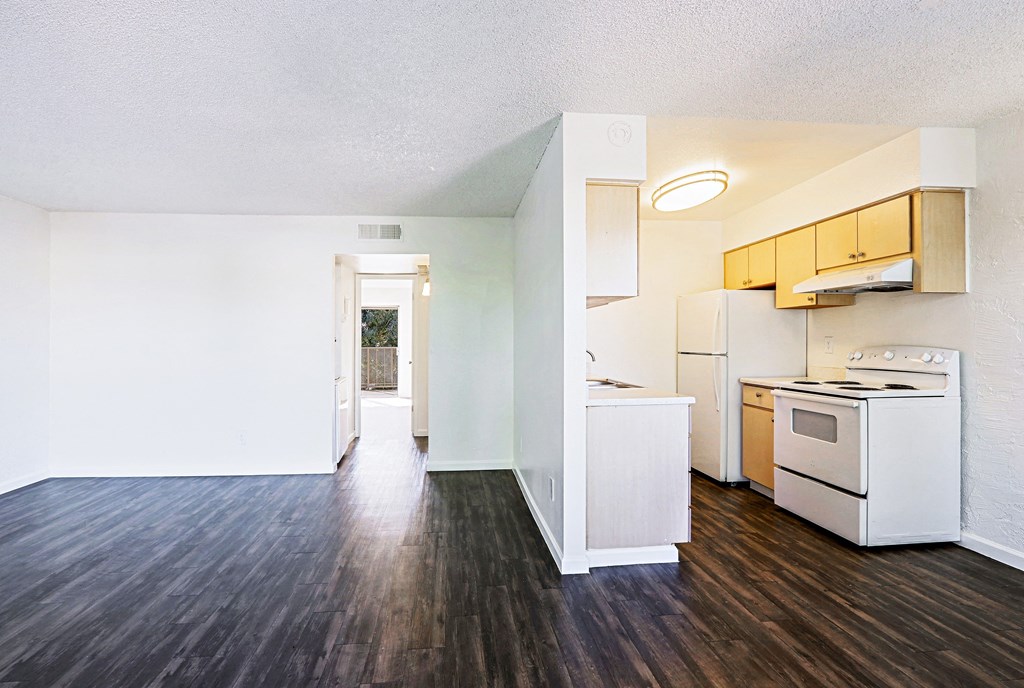 A kitchen with white appliances and wooden floors.