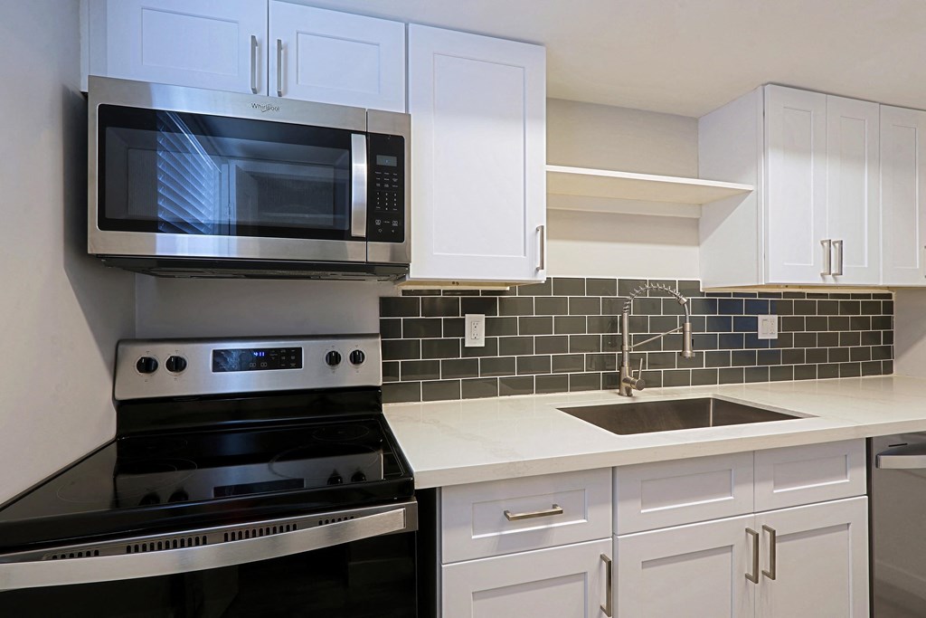A modern kitchen with white cabinets and black appliances.