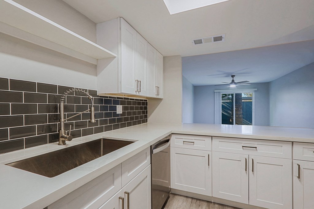 A kitchen with white cabinets and a black tile backsplash.