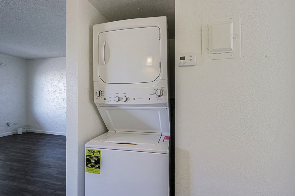 A white dishwasher with a yellow caution label on the door is in a room with white walls.