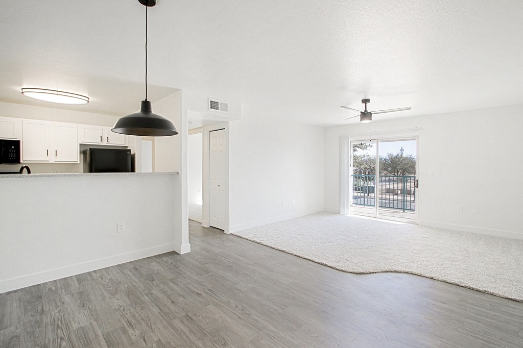 an empty living room and kitchen with a sliding glass door to a patio