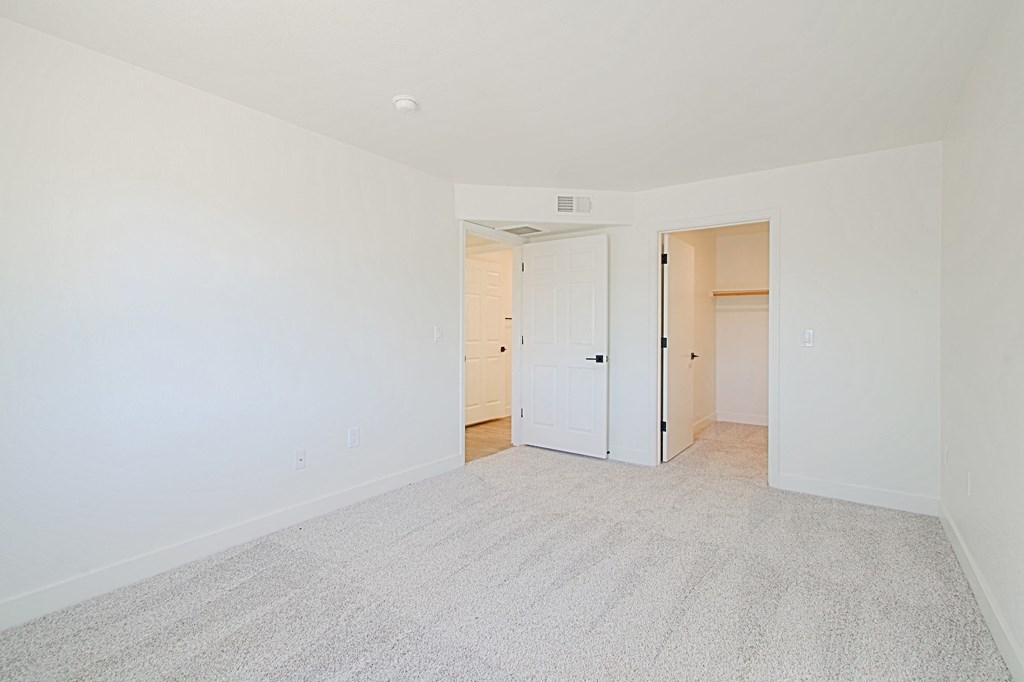 a living room with a carpet and a door to a bedroom