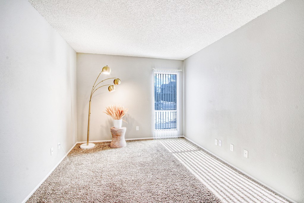 an empty room with carpet and a door to a balcony