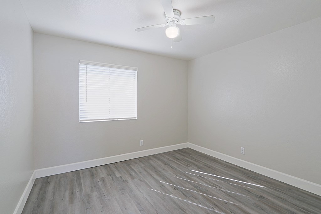an empty room with hardwood floors and a ceiling fan