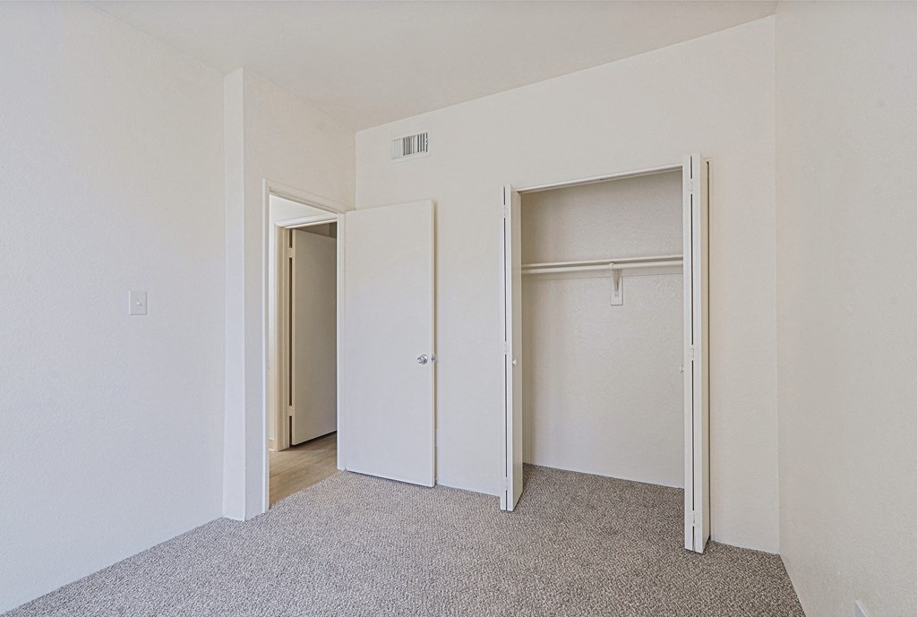 a bedroom with white walls and a closet with two doors