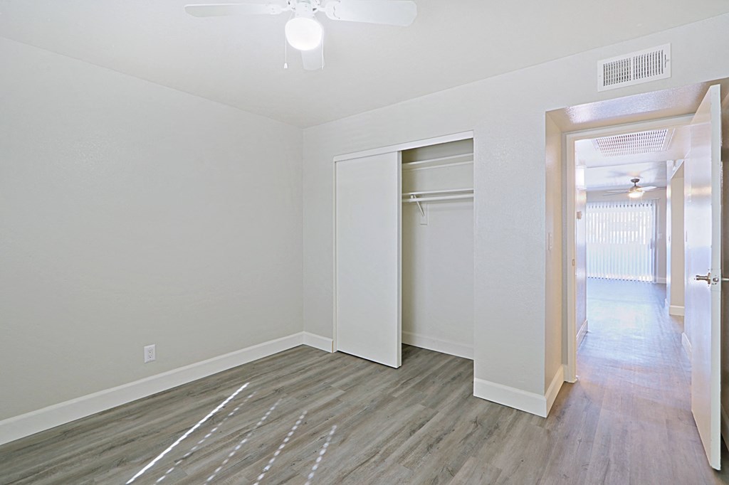 an empty bedroom with a closet and hardwood flooring