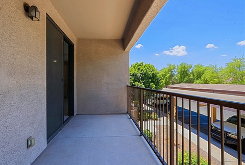 the spacious balcony has a view of the parking lot and the trees