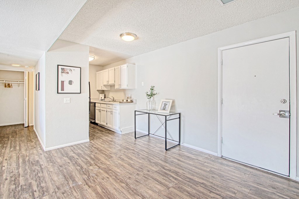 an open living room and kitchen with white walls and wood flooring