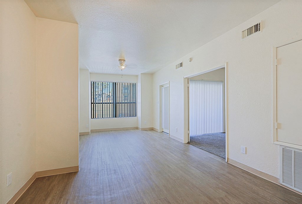 the living room and dining room of an apartment with wood flooring