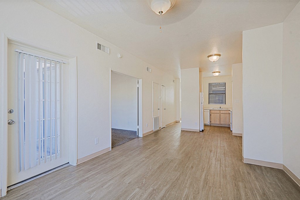 a spacious living room with white walls and wood flooring