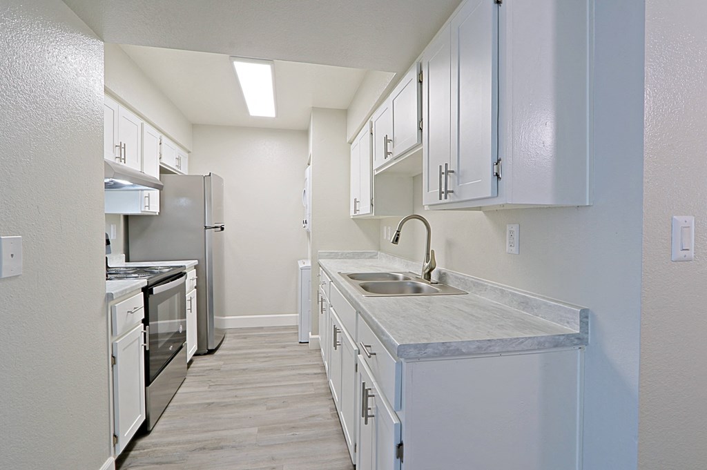 an empty kitchen with white cabinets and stainless steel appliances