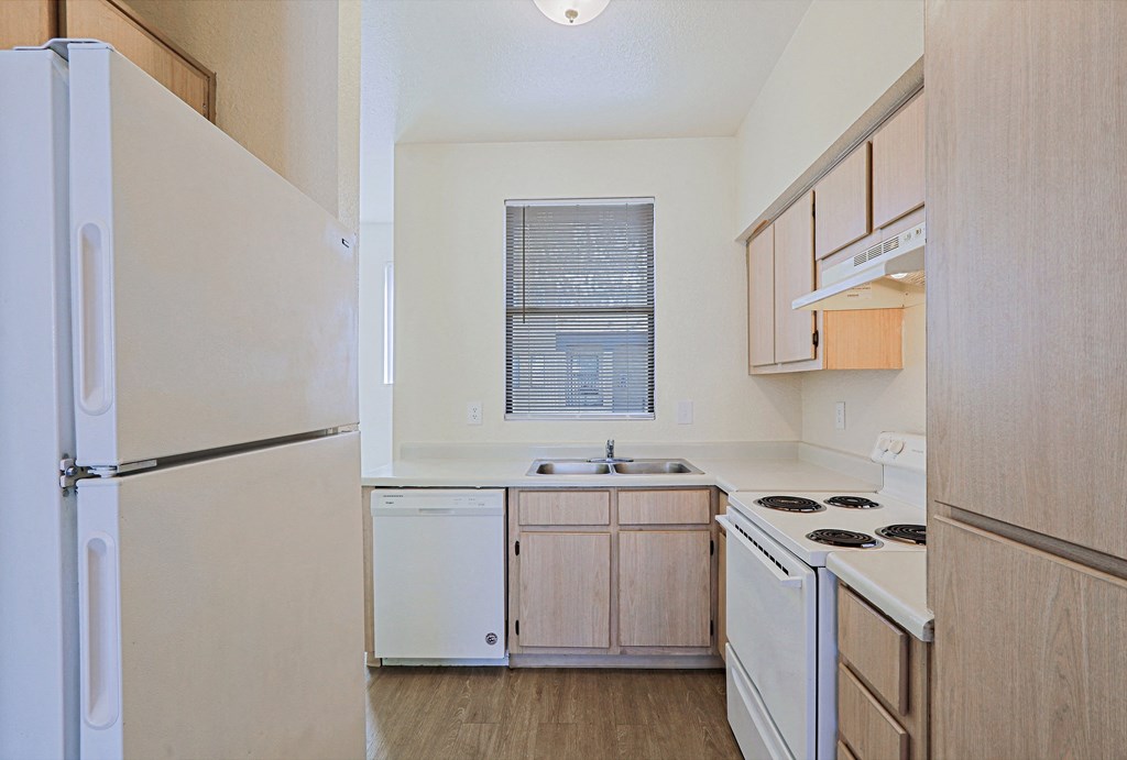 an empty kitchen with white appliances and wooden cabinets