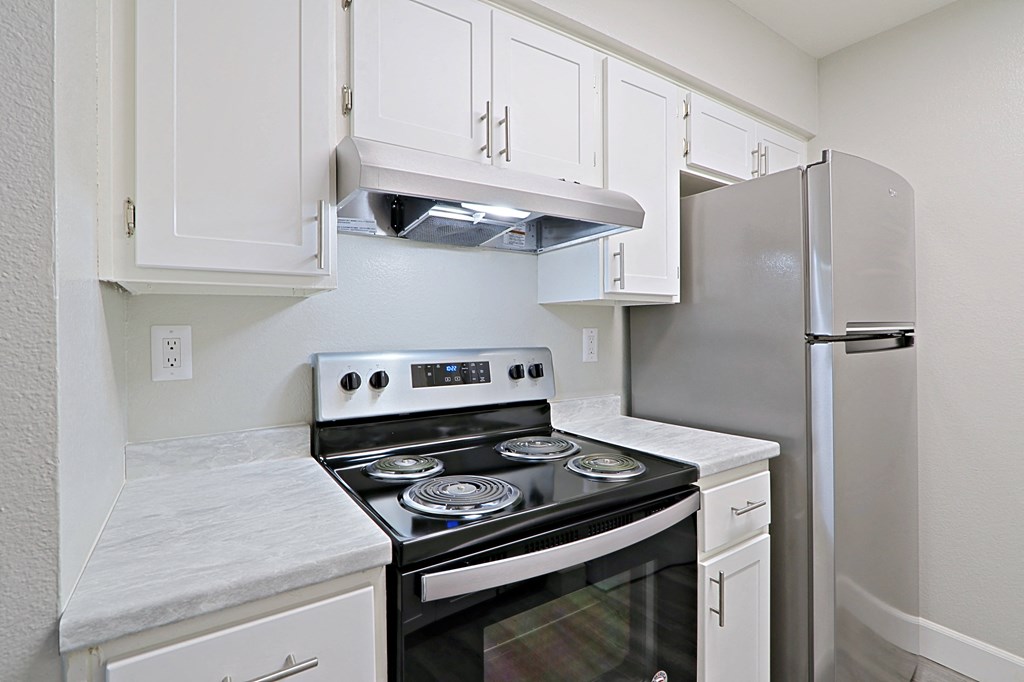 a kitchen with white cabinets and a stove and refrigerator