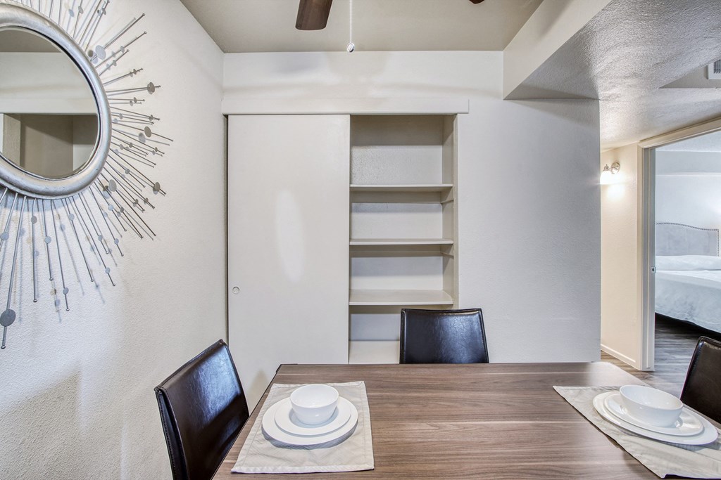 a dining room with a table and chairs and a mirror on the wall