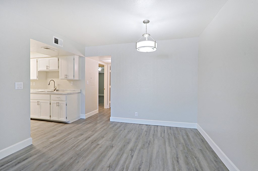 an empty living room and kitchen with wood flooring