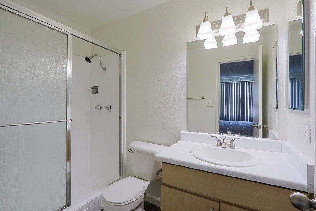 A white bathroom with a toilet, sink, and shower.