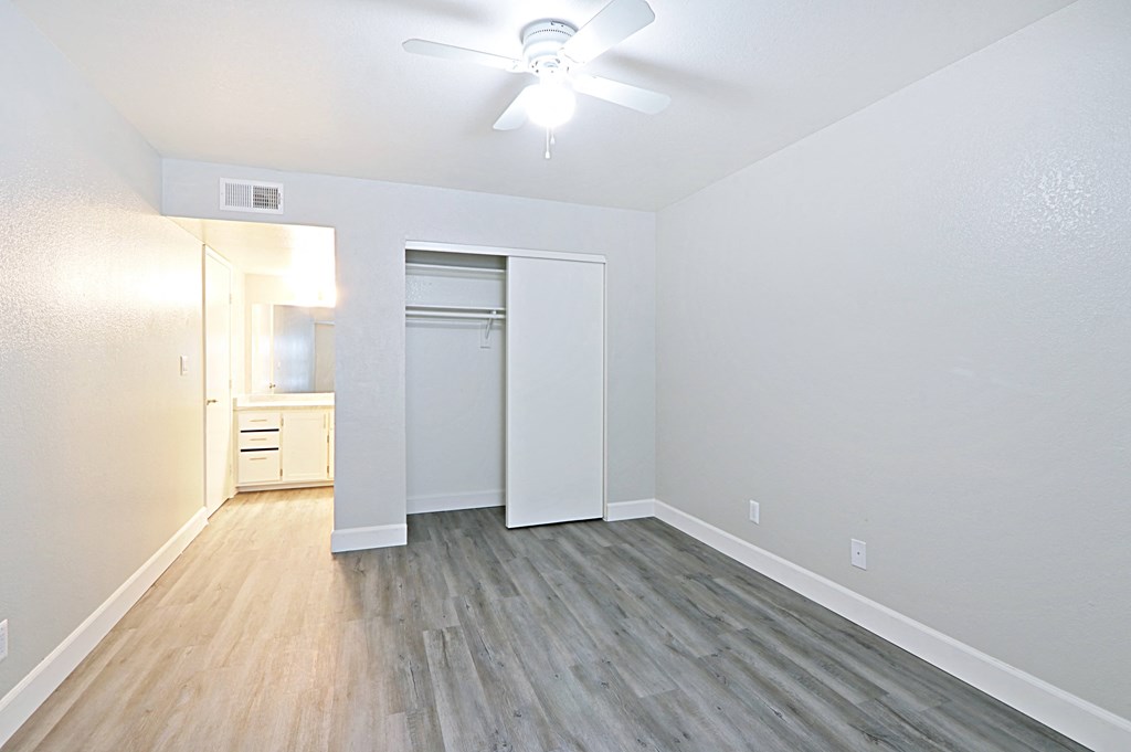 an empty living room with wood flooring and a ceiling fan