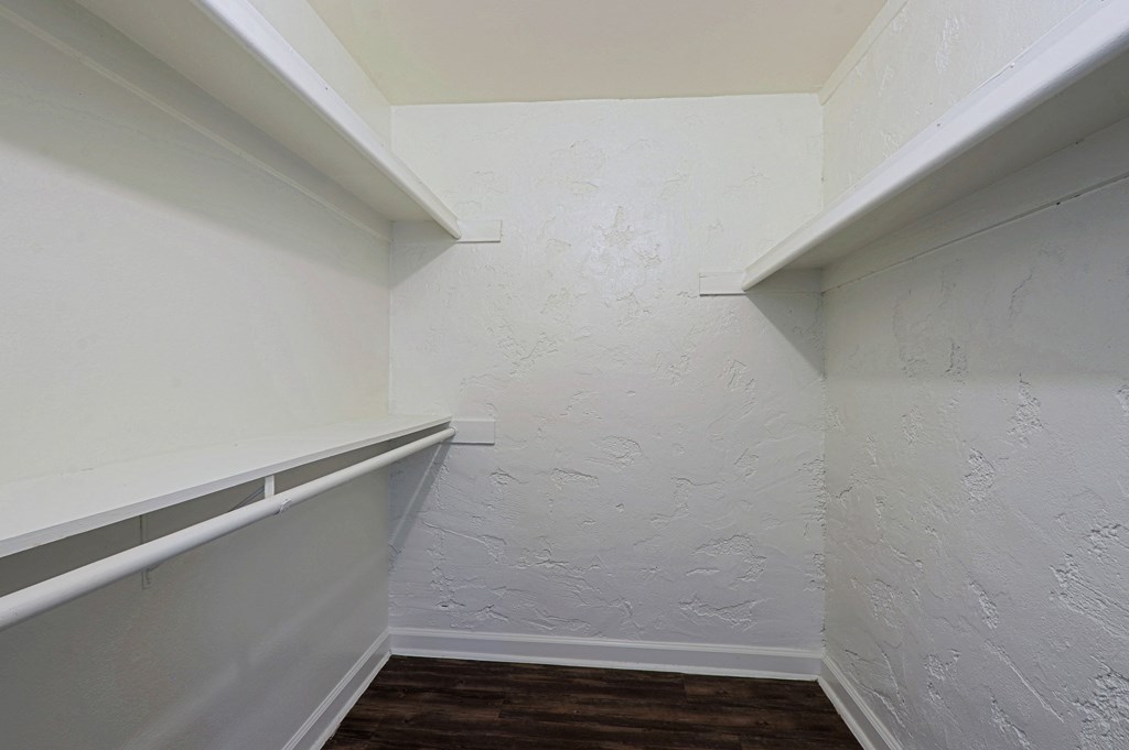 A white wall with a wooden floor and a white shelf.