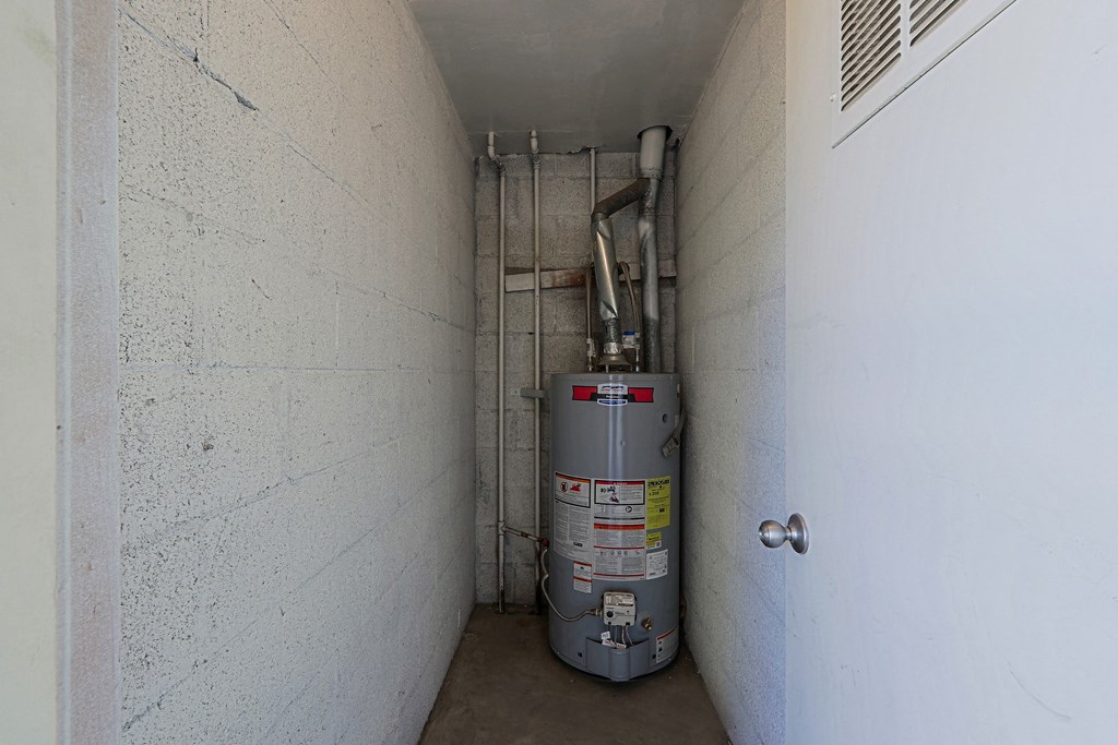 A silver metal container with red and yellow labels is in a white hallway.