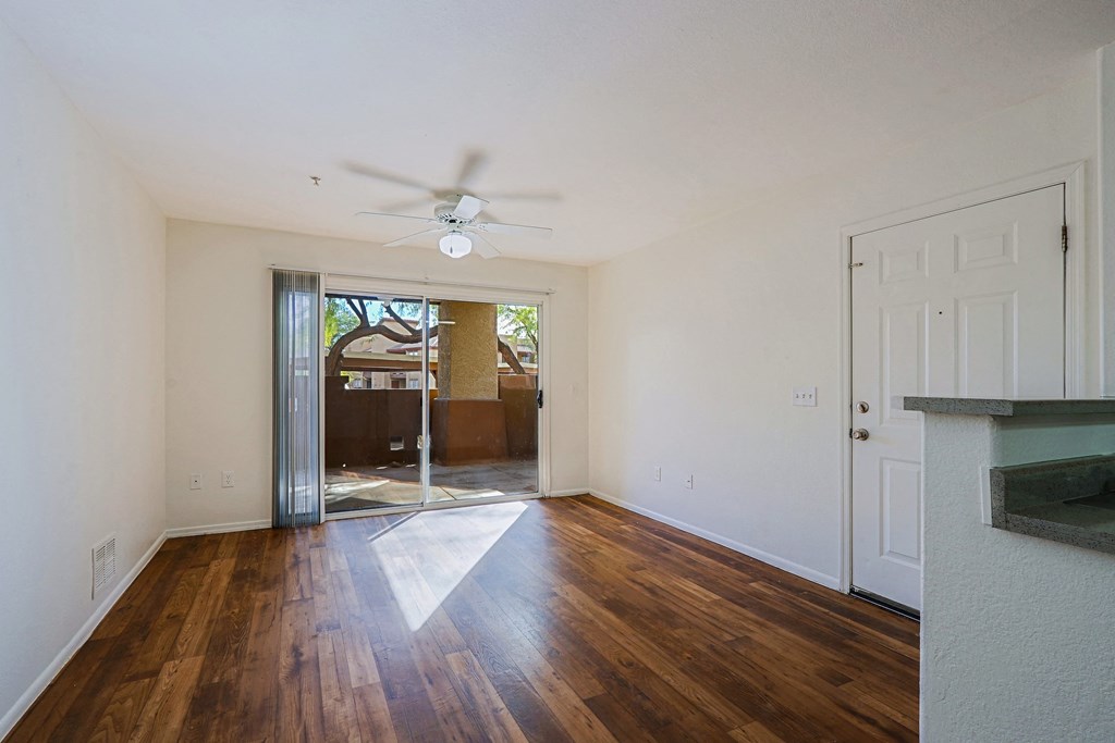 A room with a ceiling fan and wooden floors.