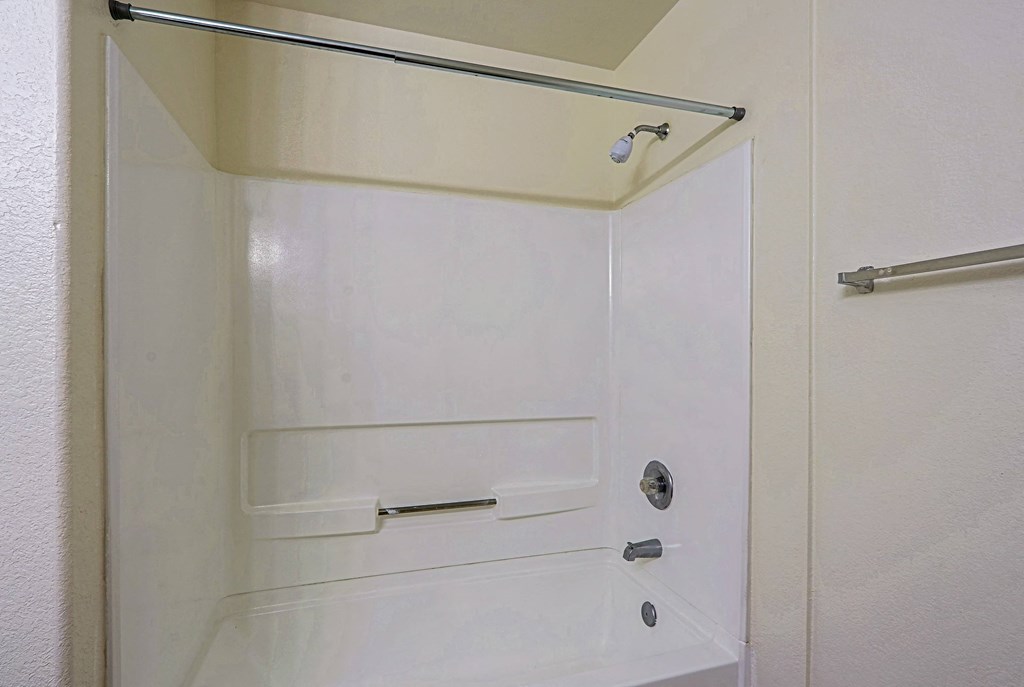 A white bathroom with a shower door open.