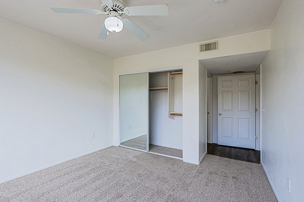 A room with a ceiling fan and carpeted floor.