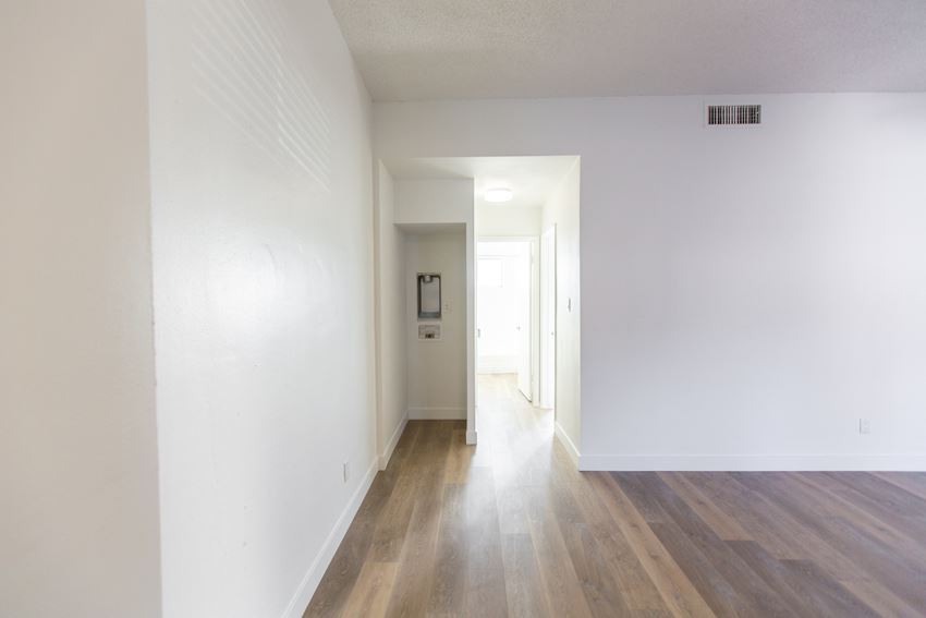 an empty living room and hallway with white walls and wood floors
