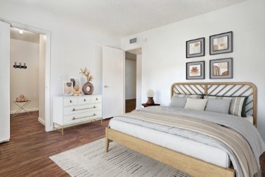 A bedroom with a large bed and a dresser with a mirror.