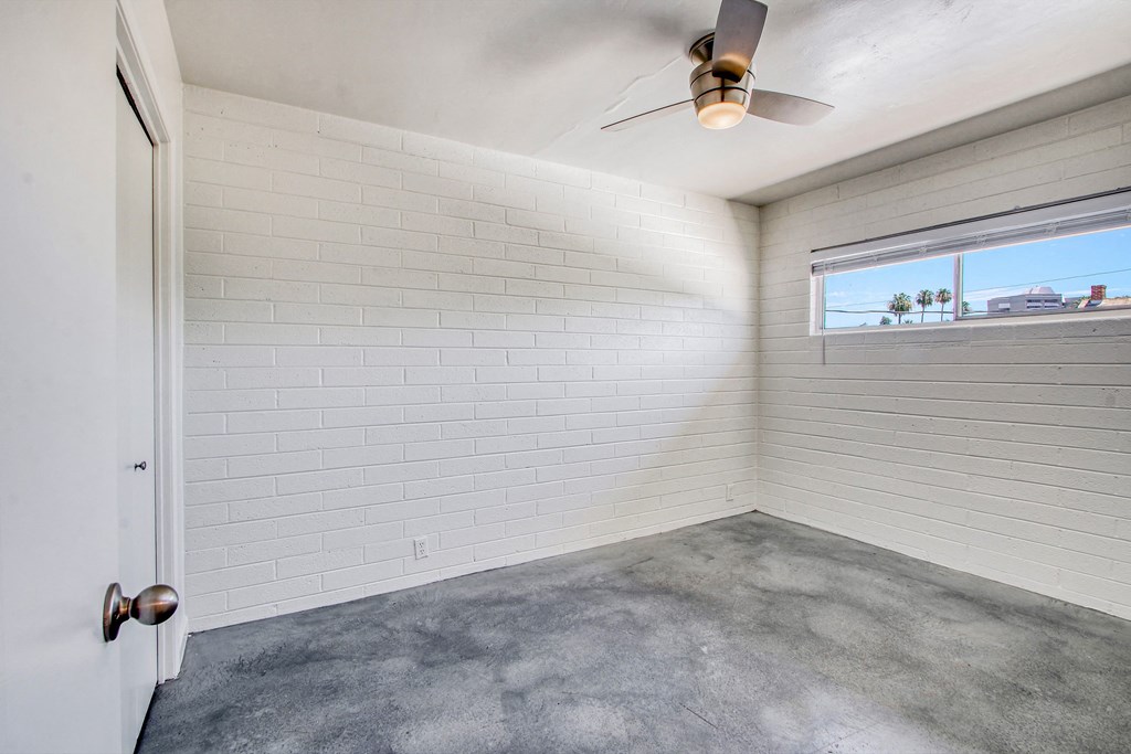 an empty room with a ceiling fan and a window