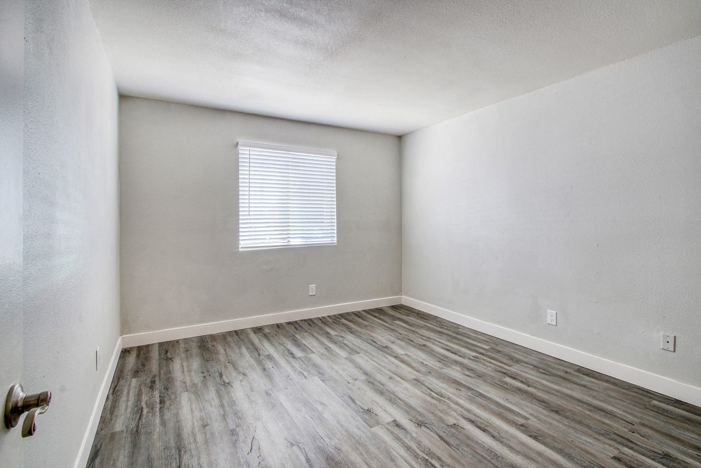 the living room of an apartment with wood flooring and a window