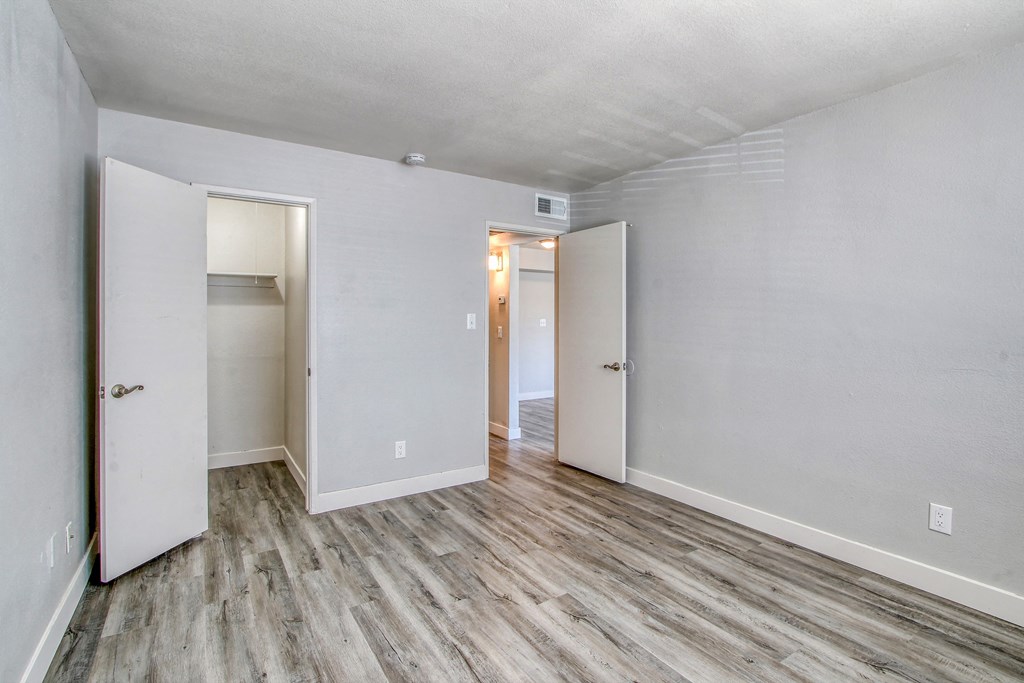 the living room of an apartment with white walls and wood flooring