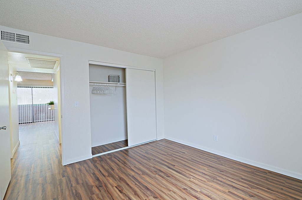 a bedroom with hardwood floors and white walls