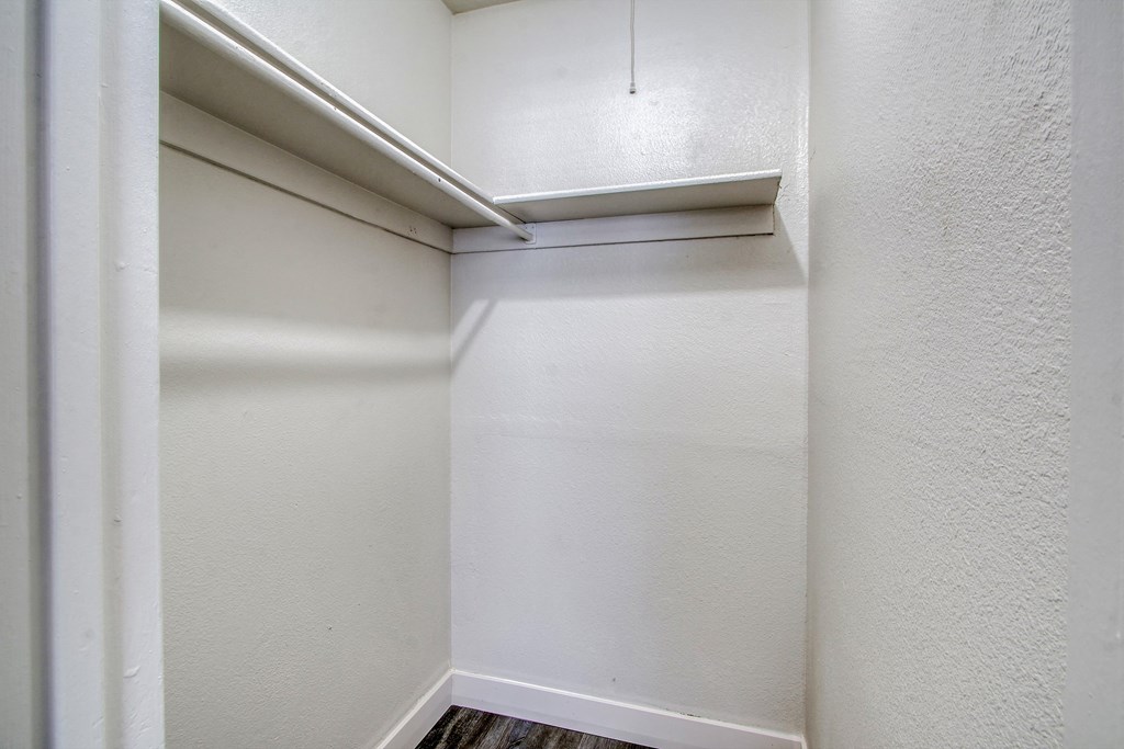 the closet in a small room with white walls and wood flooring