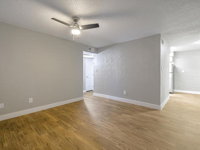 an empty living room with a ceiling fan and wood floors
