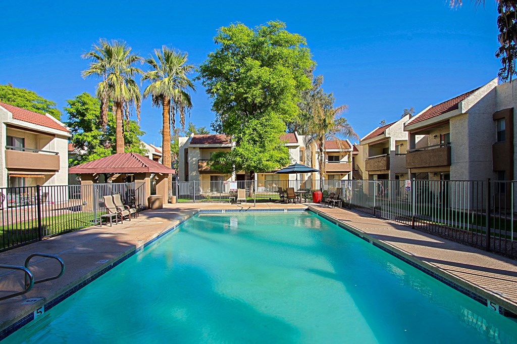 a swimming pool with palm trees and apartments in the background