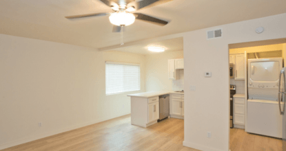A white kitchen with a ceiling fan and a window.