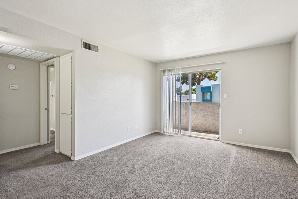 A room with a carpeted floor and a sliding glass door leading outside.