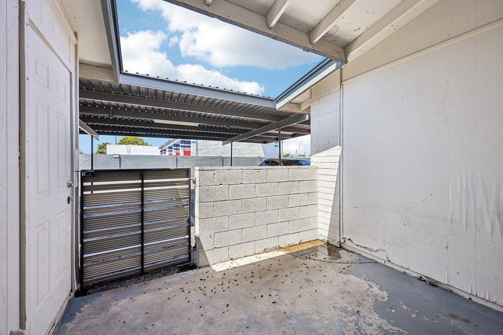 A view of a patio with a closed gate and a wall.