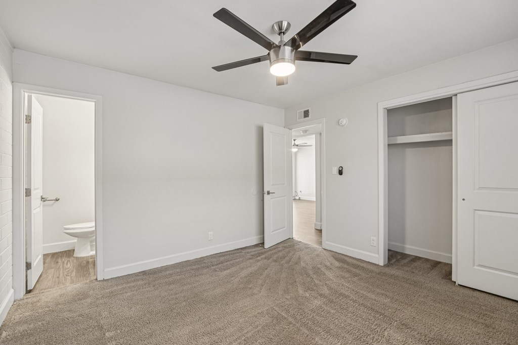 A room with a ceiling fan and carpeted floor.