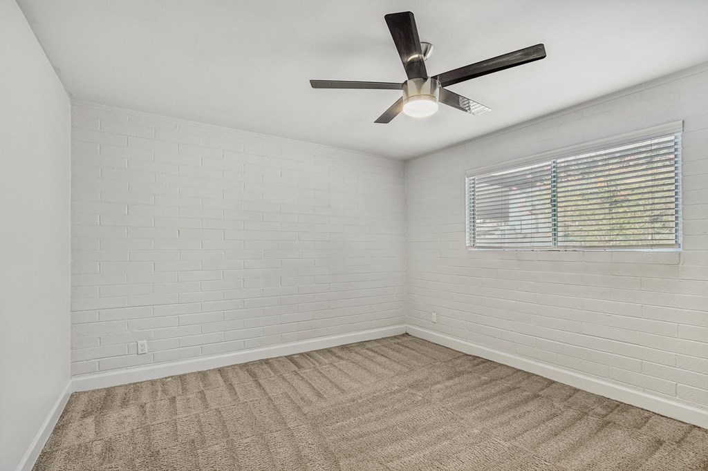 A room with a ceiling fan and a window with blinds.