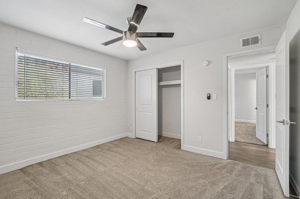A room with a ceiling fan and a window with blinds.