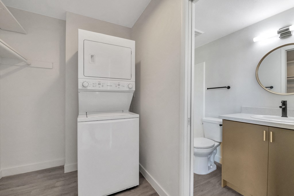 a white washer and dryer in a room with a sink and a toilet