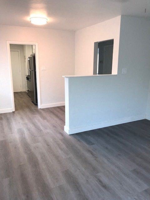 an empty living room with a blue wall and wood floors