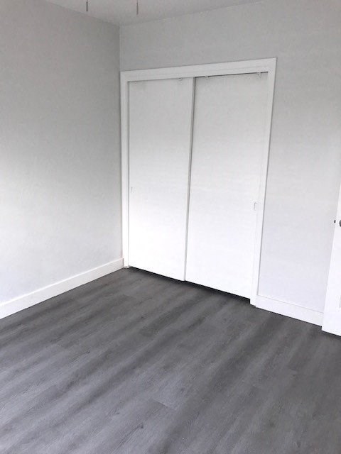 an empty room with white closet doors and a wood floor