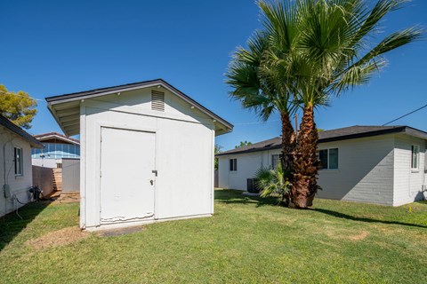 A white garage with a palm tree in front of a house.