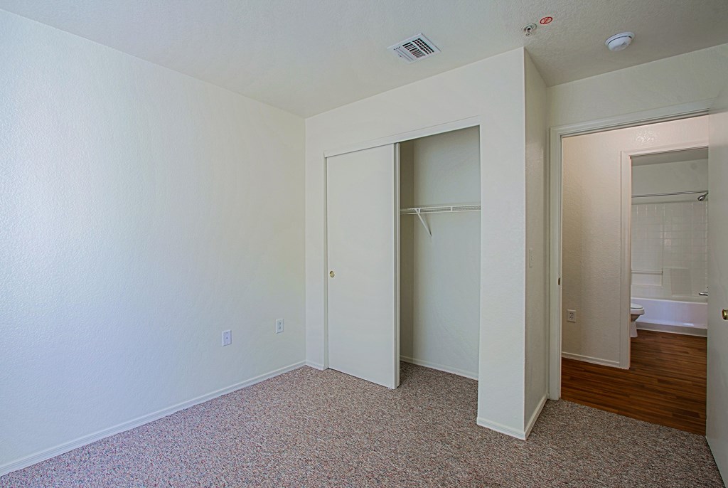 A room with a carpeted floor and a doorway leading to a bathroom.
