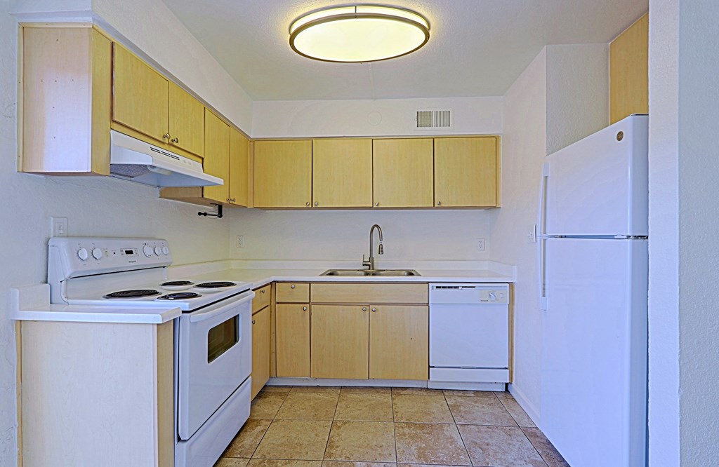 A kitchen with white appliances and wooden cabinets.