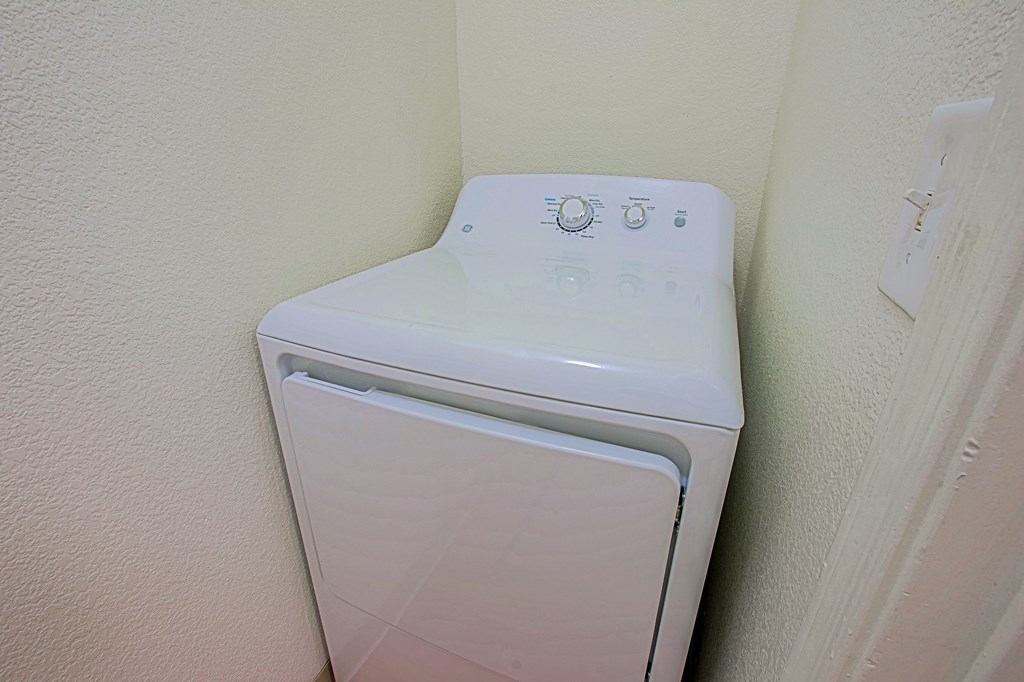A white washing machine in a corner of a room.