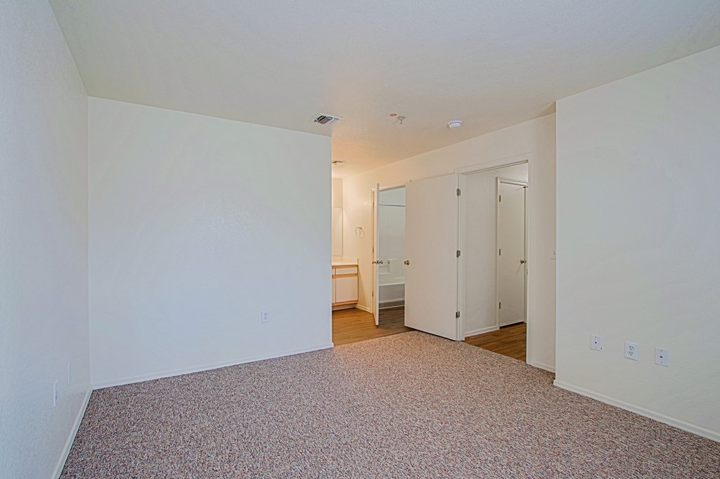 A large empty room with a carpeted floor and white walls.